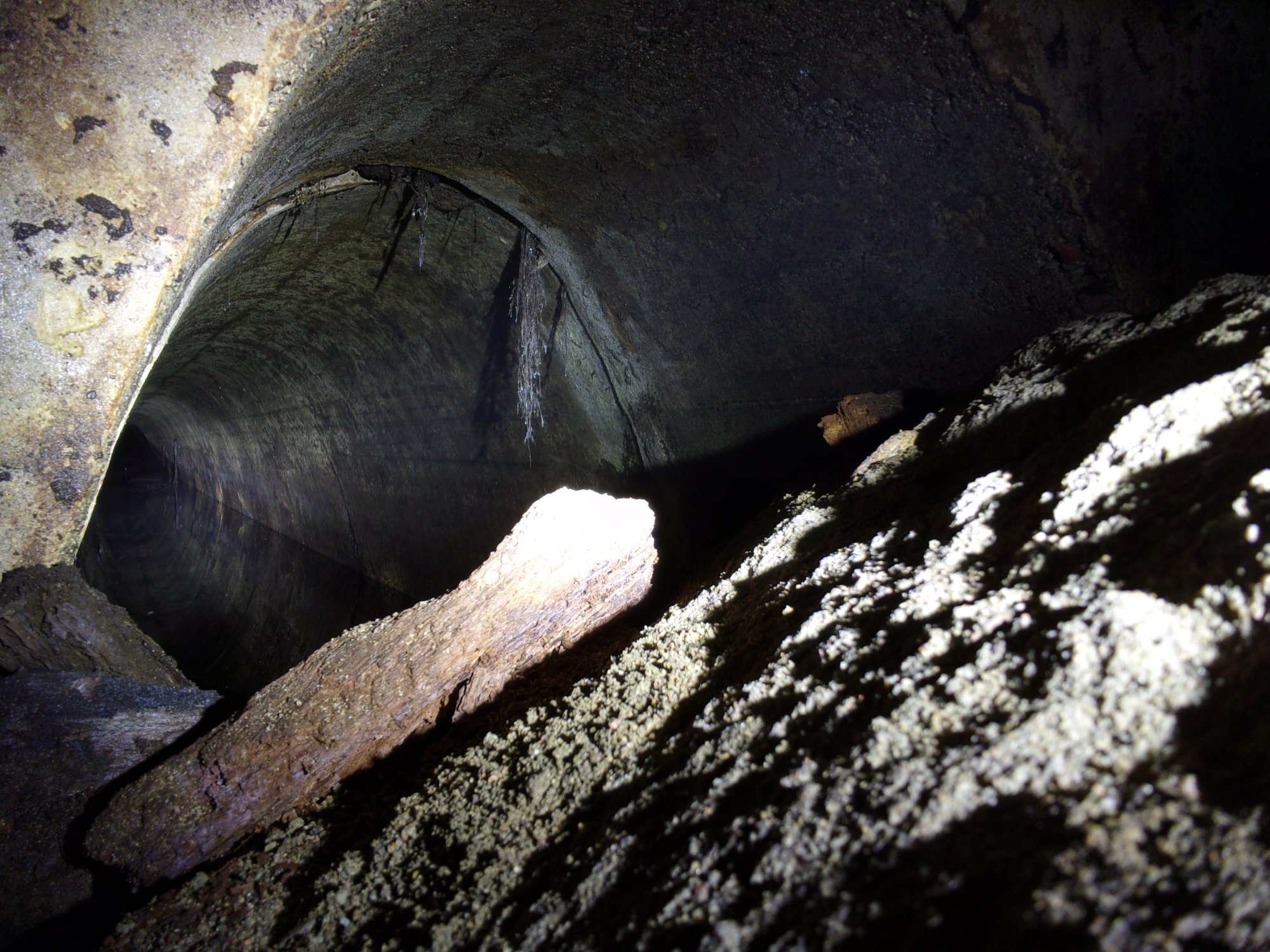 Widok na niedostępną część tunelu. Aparat wsunięty w szpary śluzy.